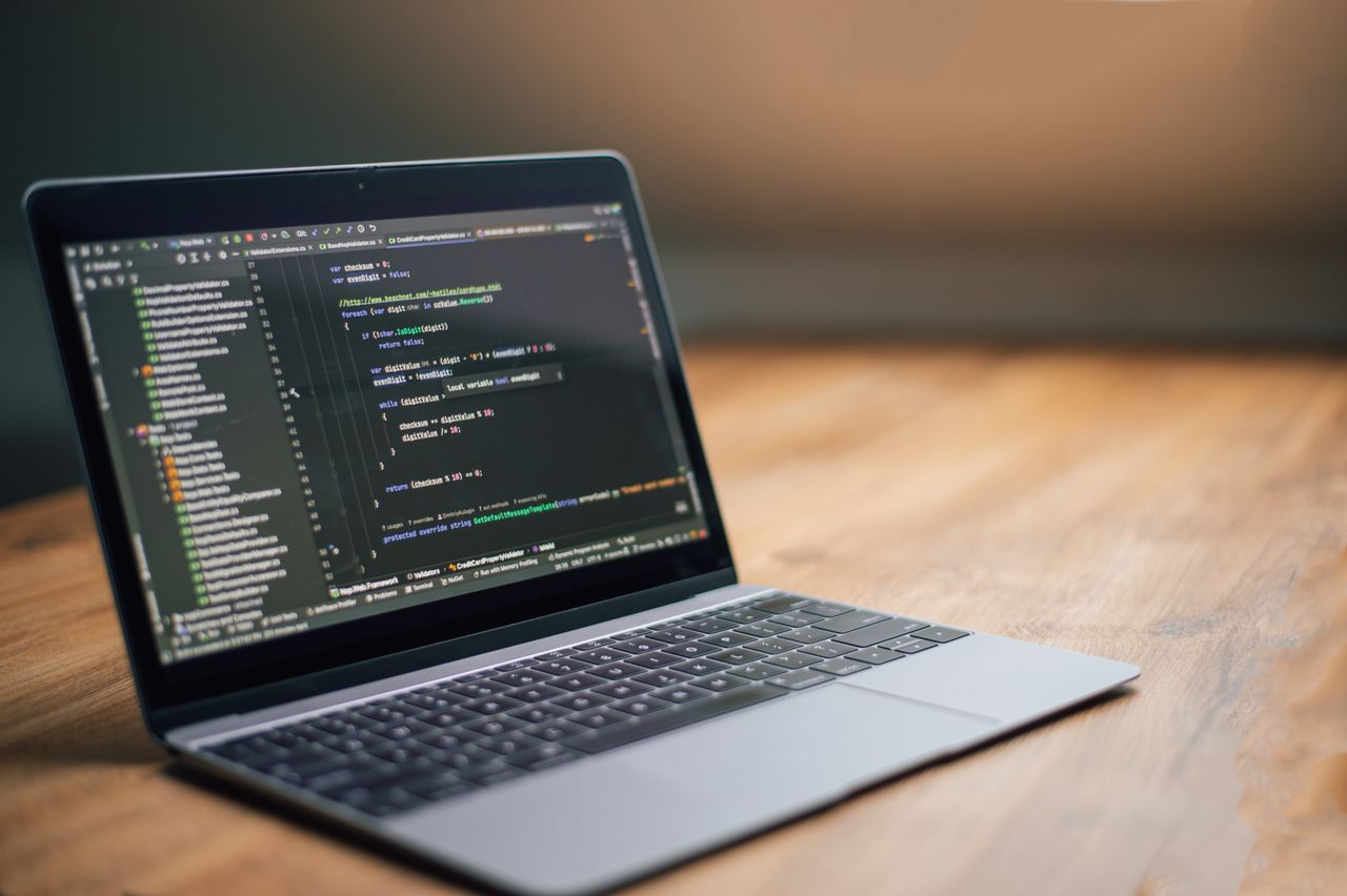 Laptop displaying software code on a wooden table, ideal for tech and programming themes.