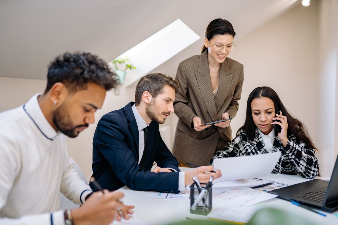 get-in-touch Group of professionals collaborating in a bright, modern office environment with digital devices.